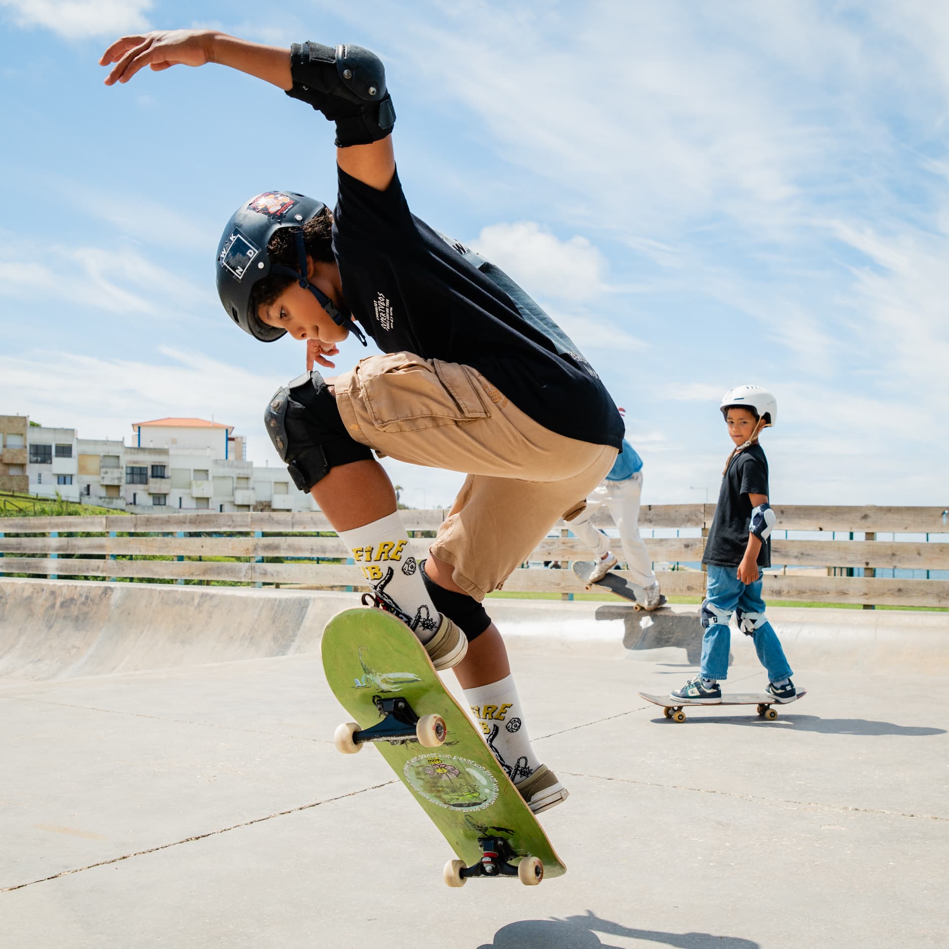 Un garçon avec casque et protections réalise une figure au skatepark