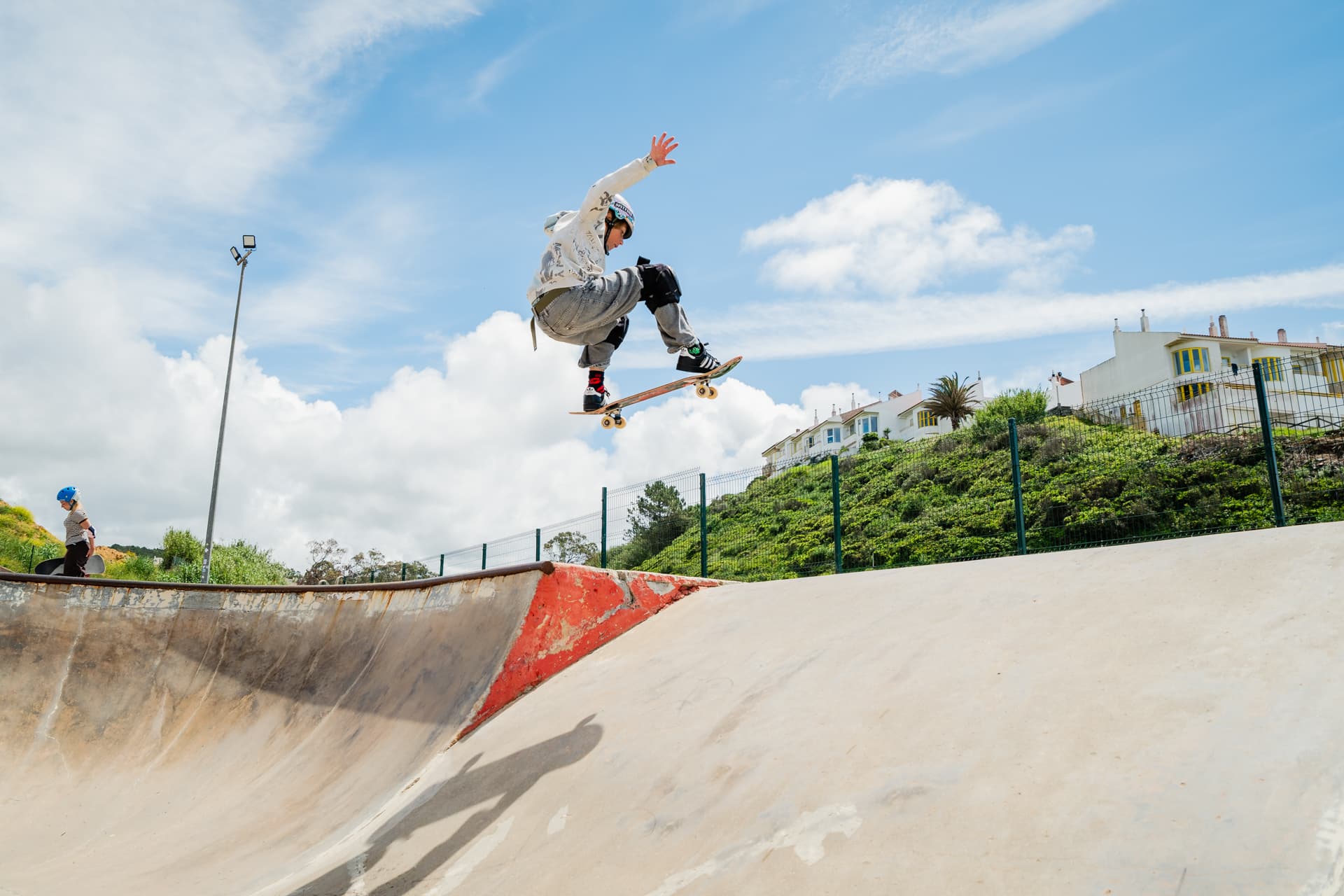 Un garçon prend de l'air avec son skateboard au-dessus du bowl au skatepark